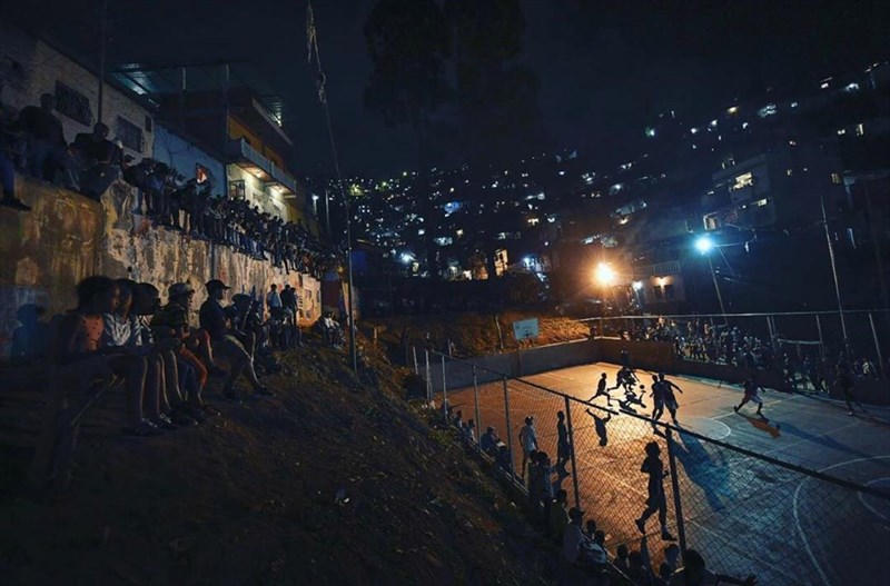 ساکنان یک محله در شهر کاراکاس، پایتخت ونزوئلا یک مسابقه بسکتبال را تماشا می کنند.